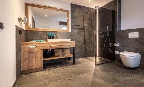 a bathroom with a sink and a toilet and a mirror at FOR MOMENTS Apartments & Spa in Roßhaupten