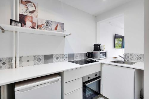 une cuisine blanche avec un évier et un micro-ondes dans l'établissement Magnificent apartment - 2BR-6P - Levallois-Perret, à Levallois-Perret