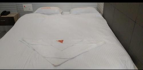 Una cama blanca en una habitación con un triángulo rojo. en Panneer residency, en Tiruvannāmalai