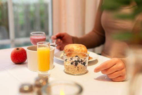 a person sitting at a table with breakfast foods and orange juice at ProfilHotels President in Norrköping