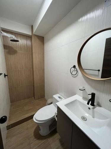 a bathroom with a toilet and a sink and a mirror at Departamento en Ibarra, Cerca a todo in Ibarra