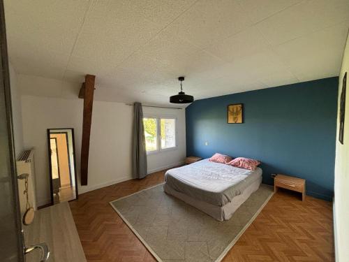 une chambre avec un lit et un mur bleu dans l'établissement La loge, à Bouchamps-lès-Craon