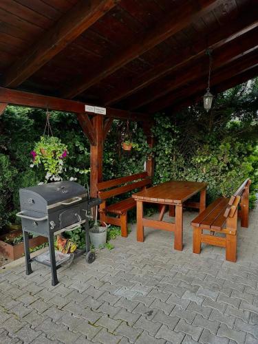 a patio with a picnic table and a grill and a bench at Chalupa Synka in Terchová