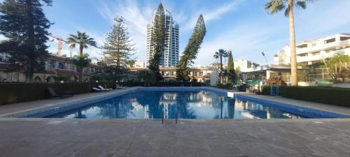 a large swimming pool with palm trees and buildings at Coco De Mer 408 in Limassol