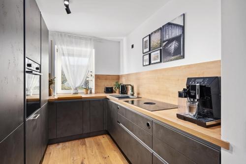 eine Küche mit schwarzen Schränken und einer Arbeitsplatte mit einer Mikrowelle in der Unterkunft EDLER WOHNRAUM Luxuriöses Apartment mit Balkon, Boxspringbett, Kaffeevollautomat, Lift & Parkplatz in Chemnitz
