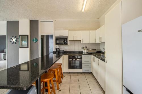 Una cocina con gabinetes blancos y una encimera negra. en Seagull 514, en Margate