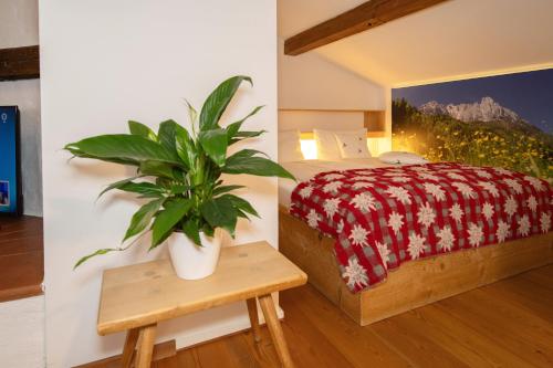 a bedroom with a bed and a plant on a table at Gästehaus Bergstüberl in Reit im Winkl