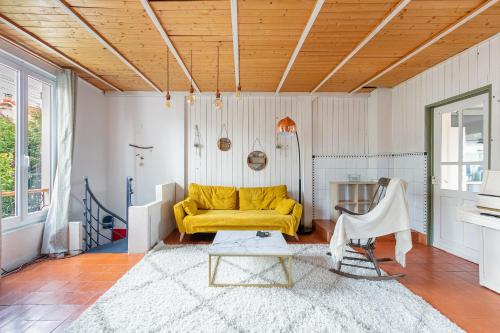 ボンディにあるMaison rustique à 11min de Paris, cadre chaleureuxの黄色いソファとテーブルのあるリビングルーム