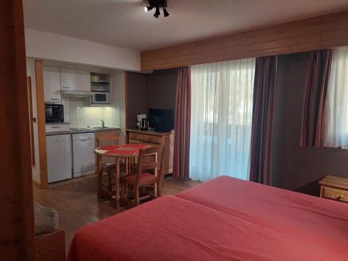 une chambre avec un lit et une cuisine avec une table dans l'établissement Studio cosy au cœur de Brides-les-Bains, balcon, wifi, parking, animaux admis - FR-1-512-282, à Brides-les-Bains