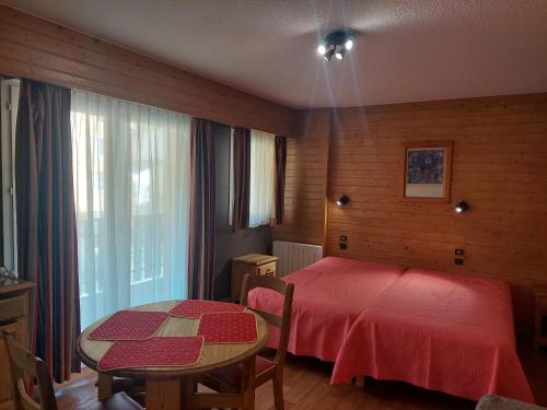 - une chambre avec un lit rouge et une table dans l'établissement Studio cosy au cœur de Brides-les-Bains, balcon, wifi, parking, animaux admis - FR-1-512-282, à Brides-les-Bains