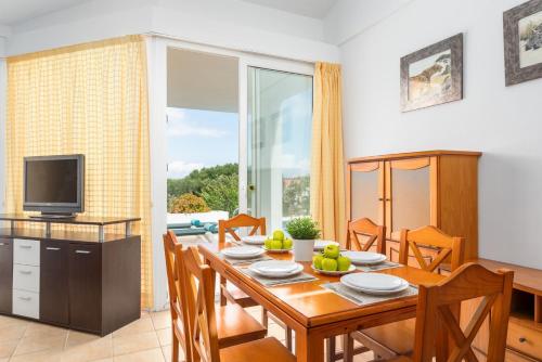 a dining room with a table with chairs and a television at Villa Elena Dorada in Port d'Addaia