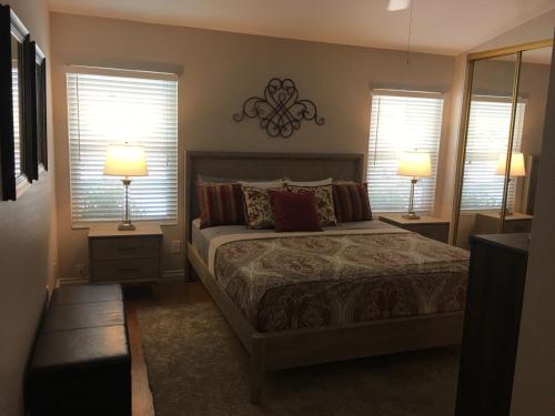 a bedroom with a bed with two lamps and two windows at Tranquil 3BR Home w Private Pool Spa in La Quinta