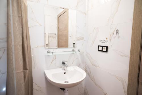 a white bathroom with a sink and a mirror at RIVER SIDE in Polyana