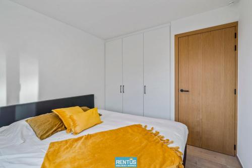 a bedroom with a bed with a yellow blanket on it at Sol i Mar - located in the heart of Westende in Middelkerke