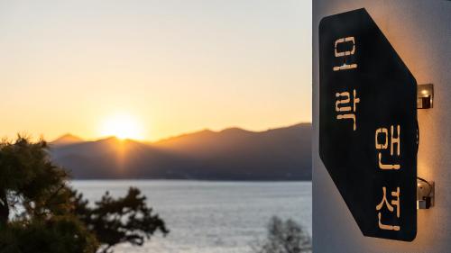 a sign with the sunset in the background at Namhae Mansion Morak in Namhae