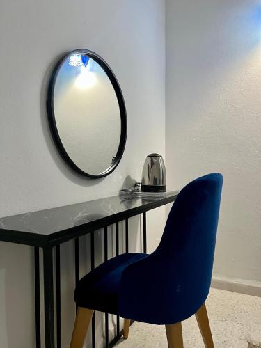 a blue chair sitting next to a table with a mirror at Dar Ali - Guesthouse in Tozeur