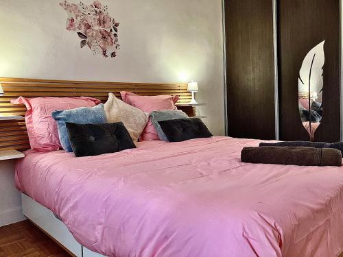 - un grand lit avec des draps et des oreillers roses dans l'établissement Parisian Lounge 8 pers Front station, à Villemomble