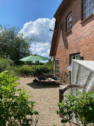a patio with a table and an umbrella in front of a building at Hoheluft am Wittensee Apt 1 in Groß Wittensee