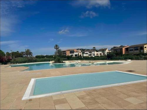une piscine dans une cour avec des bâtiments en arrière-plan dans l'établissement Proche St Tropez refait à neuf bord de plage et piscine, à Cogolin