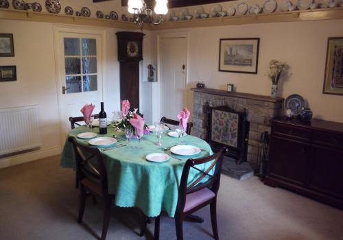 a dining room with a table with chairs and a fireplace at Corner House in Grinton