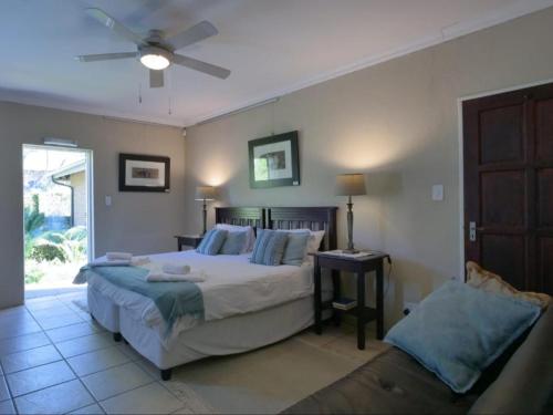 a bedroom with a bed and a table and a fan at Forest and Ferns in Graskop