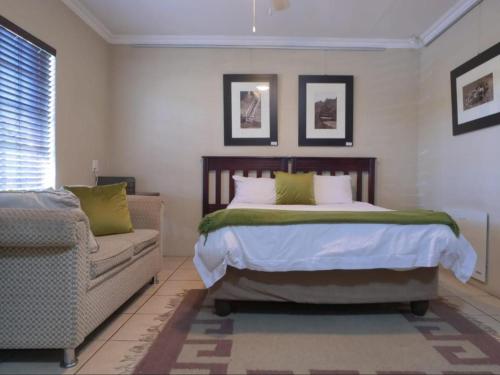 a bedroom with a bed and a couch at Forest and Ferns in Graskop