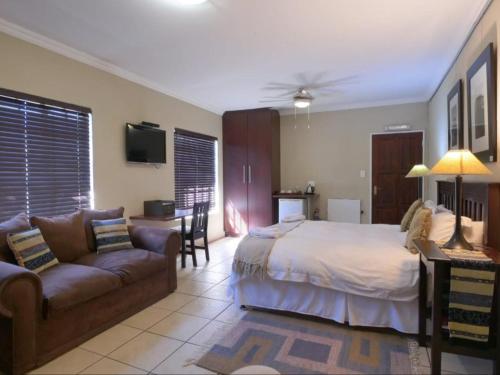 a large bedroom with a bed and a couch at Forest and Ferns in Graskop