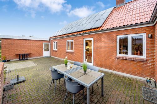 a patio with a table and chairs and a brick building at Lovely Holiday House With 4 Rooms Close To The North Sea in Frøstrup