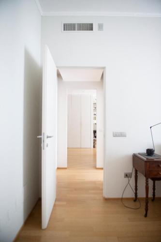 a hallway with white walls and a table and a piano at Il Cenacolo Milano Centro Cadorna Santambrogio comodo per Fiera e Allianz Milano Convention Centre in Milan