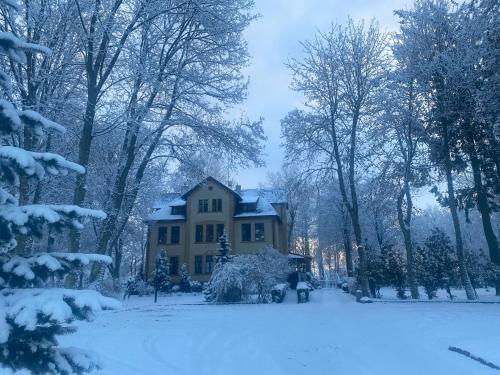 a house covered in snow in a yard at Pałac Poraj in Wicko