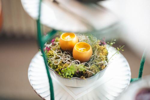 two eggs are sitting on a plate with plants at Mandarin Oriental Palace, Luzern in Lucerne