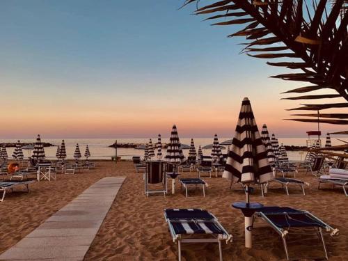 Un grupo de sillas y sombrillas en una playa. en House 80palmi, en Catania