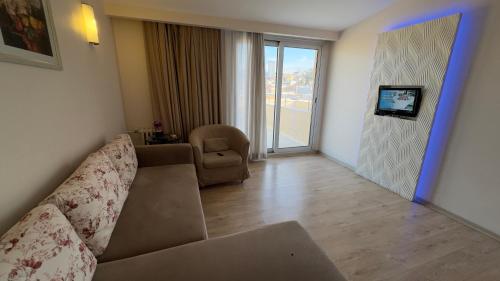a living room with a couch and a chair and a television at Hotel Baylan İzmir in Izmir