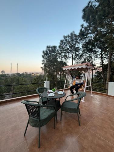 a woman sitting on a swing on a patio with a table and chairs at 4BR cozy villa kasauli garden bone fire open terrace jhula by the north edge in Dagshai