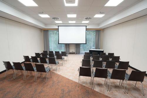 a conference room with chairs and a projection screen at Radisson Blu Hotel Dortmund in Dortmund