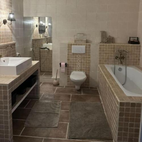 une salle de bain avec une baignoire, des toilettes et un lavabo dans l'établissement Magnifique Mas familial - 18 personnes, à Sagriès