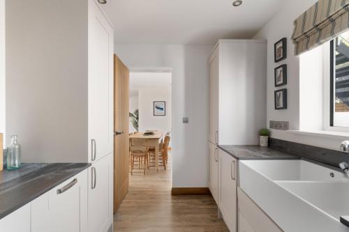 a kitchen with white cabinets and a dining room at Ranalegh Court in Saint Columb Minor