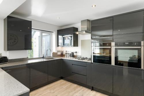 a large kitchen with black cabinets and appliances at Ranalegh Court in Saint Columb Minor