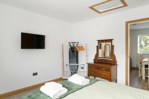 a bedroom with a bed and a mirror and a dresser at Ranalegh Court in Saint Columb Minor