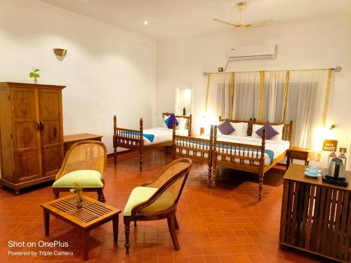 a bedroom with two beds and chairs in a room at Marari Beach Bungalow Resort Alleppey in Mararikulam