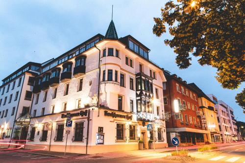a large white building with a tower on a street at PLAZA Hotel Buchhorner Hof in Friedrichshafen
