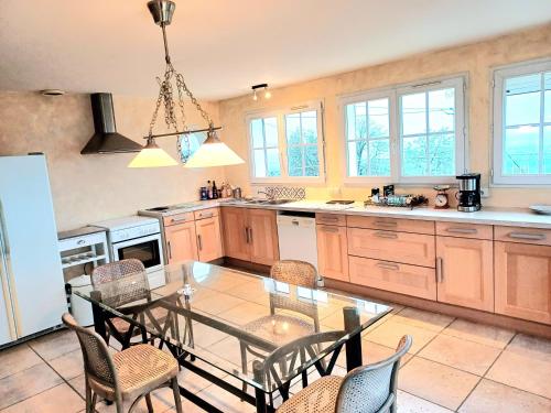 une cuisine avec une table en verre et des chaises. dans l'établissement Le Petit Château, à LʼÉtoile