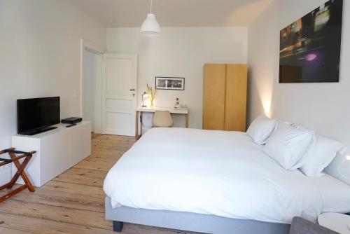 a bedroom with a large white bed and a television at B&B Home & the City in Brussels