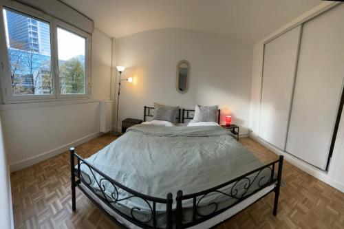 un lit dans une chambre avec une grande fenêtre dans l'établissement Cozy 1BR apartment, 5mn to métro, in La Défense, à Courbevoie
