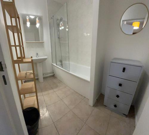 une salle de bain avec une baignoire, un lavabo et un miroir dans l'établissement Cozy 1BR apartment, 5mn to métro, in La Défense, à Courbevoie