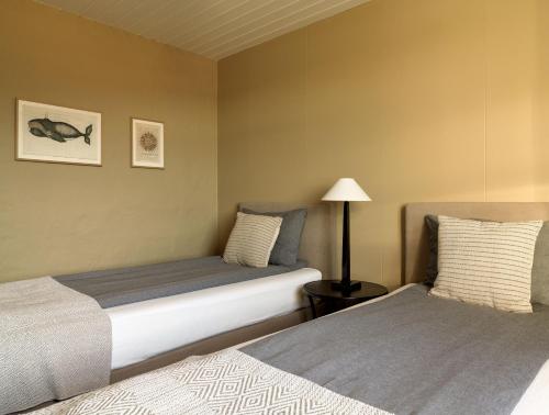 a bedroom with two beds and a lamp in it at Hvammsvík Nature Resort in Kjósahreppur