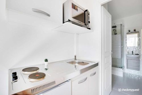 une cuisine blanche avec un évier et une cuisinière dans l'établissement Charming studio - 2P - Near Convention, à Paris