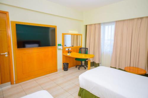 a hotel room with a bed and a desk and a television at Holiday Inn Dar Es Salaam by IHG in Dar es Salaam