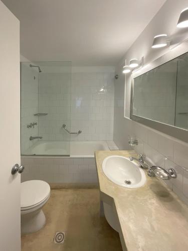 a bathroom with a sink and a toilet and a tub at La Posta Beach Hotel in Punta del Este