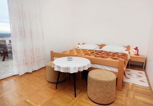 ein Schlafzimmer mit einem Bett und einem Tisch und einem Fenster in der Unterkunft Apartment Ljerka in Malinska